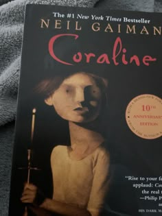 the book coraline by neil gaiman is laying on top of a gray blanket