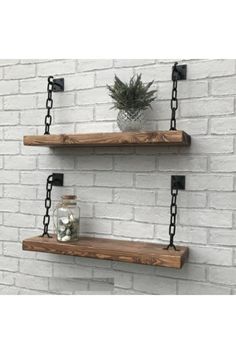 two wooden shelves with metal chains hanging from them on a brick wall next to a potted plant