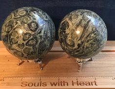 two metal balls sitting on top of a wooden table next to a measuring ruler with the words soul's with heart written below it