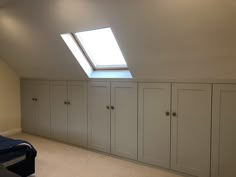 an attic bedroom with white cabinets and skylight