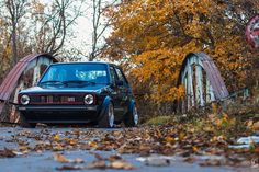 a black car parked on the side of a road next to a bridge and trees