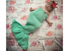 a newborn baby girl wearing a green crochet mermaid tail sleeping on a floral blanket