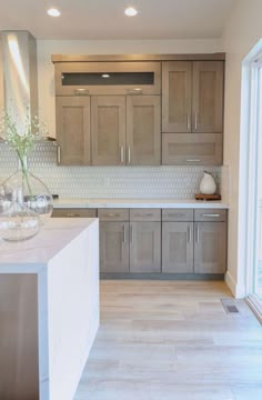 a large kitchen with wooden cabinets and marble counter tops, along with glass vases on the island