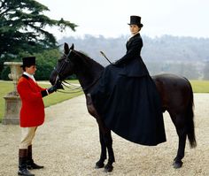 a man standing next to a woman on top of a horse