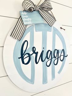 a wooden sign with the word brugo painted on it and a bow tied around it