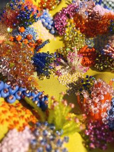 many different colored beads on a yellow cloth with blue and orange flowers in the center