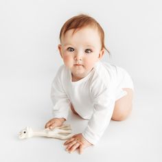 a baby is laying on the floor with a bone in front of him and looking at the camera