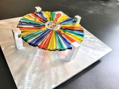 a multicolored object sitting on top of a metal plate