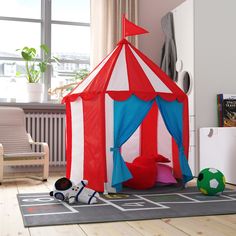 a play tent in the middle of a room with toys on the floor and a soccer ball