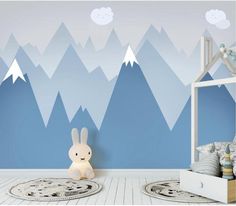 a child's room with mountains painted on the wall and a stuffed bunny in the corner