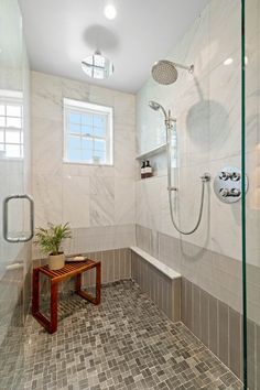 a tiled bathroom with a bench and shower head in it's corner, next to a window