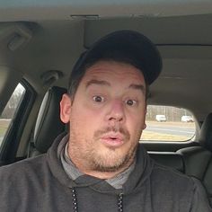 a man sitting in the back seat of a car with a surprised look on his face