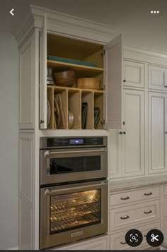 an oven built into the side of a cabinet in a kitchen with white cupboards