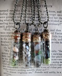 three glass bottles filled with sand and sea shells on a chain hanging from a book