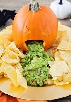 a plate with chips, guacamole and a jack - o'- lantern