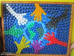 a man standing next to a giant lego board with different colored handprints on it