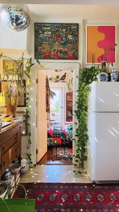 a kitchen with a refrigerator and lots of plants on the wall next to an open door