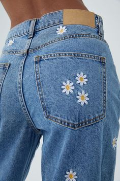 the back view of a woman's jeans with daisies on it and an inner pocket