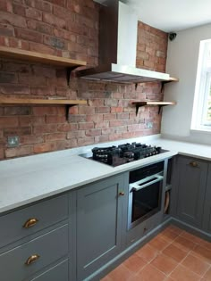 a kitchen with grey cabinets and white counter tops, an oven and window in the background