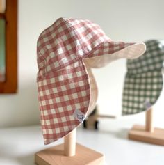 two hats sitting on top of wooden stands in front of a mirror, one with a red and white checkered hat