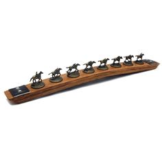 a wooden board with figurines of horses and jockeys on the front, sitting on top of each other