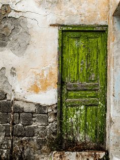 an old door is painted green on the side of a building