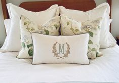 a bed with white sheets, pillows and a monogrammed letter m on it