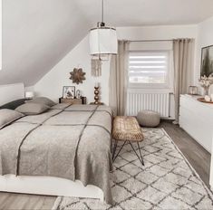 a bed sitting under a window in a bedroom next to a white dresser and chair