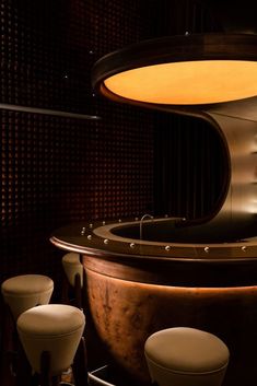 a bar with three stools and a round table in the middle, surrounded by brown walls