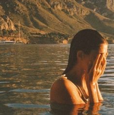 a woman sitting in the water with her hand to her face