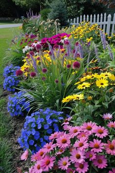 colorful flower garden in front of a white picket fence