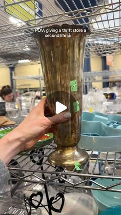 a person is holding a vase with stickers on it in a room full of other items