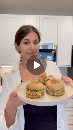 a woman holding a plate with sandwiches on it