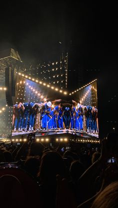 a group of people standing on top of a stage with lights in front of them