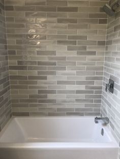 a white bath tub sitting next to a tiled wall