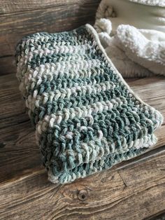 a crocheted blanket sitting on top of a wooden bench next to a pillow