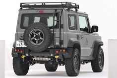 the front end of a grey jeep with black tires and bumper guards on white background