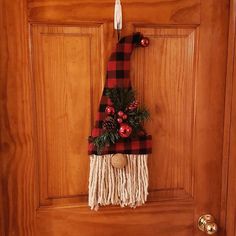 a door hanger decorated with christmas decorations and pine cones on a wooden front door