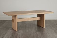 a wooden table sitting on top of a hard wood floor next to a white wall