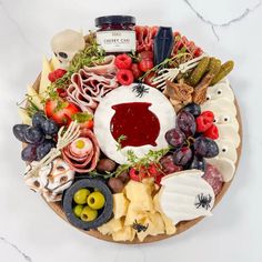 a platter filled with cheese, meats, and fruit on top of a marble table