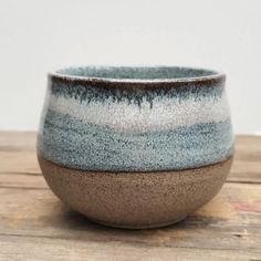 a blue and brown bowl sitting on top of a wooden table next to a white wall