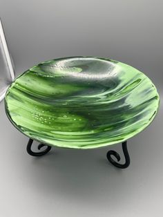 a green glass bowl sitting on top of a metal stand