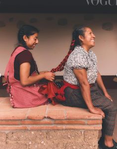 two women are sitting on a brick bench