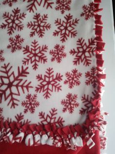 a red and white snowflake blanket on top of a table with fringes