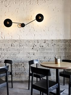 a table and chairs in front of a brick wall with two lights on the side