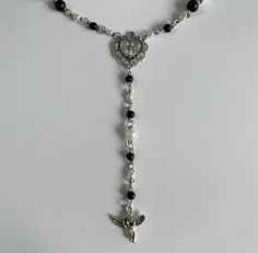 a necklace with a cross, heart and angel charm on the end is shown against a white background