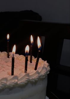 a birthday cake with lit candles sitting on top of it's white frosting