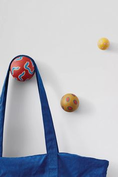 an orange and blue bag sitting next to two balls on the ground with one ball in the air