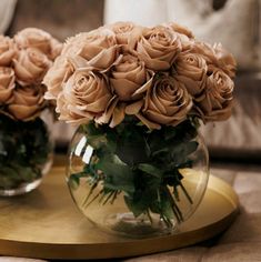 two vases filled with roses sitting on top of a wooden table next to a couch