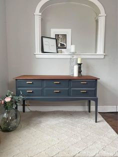 a blue dresser with two drawers and a mirror above it in a gray living room